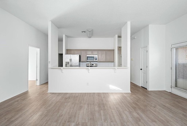 3833 Ives Way, Norman, OK 73072 - kitchen with stainless steel appliances, a peninsula, a kitchen bar, and light countertops