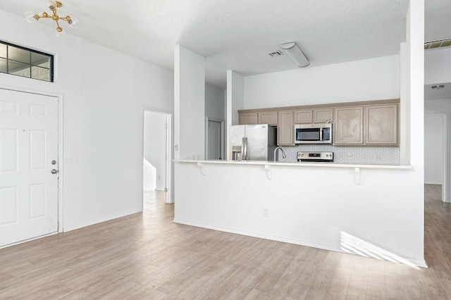 3833 Ives Way, Norman, OK 73072 - kitchen with appliances with stainless steel finishes, a kitchen breakfast bar, tasteful backsplash, light wood-type flooring, and a sink