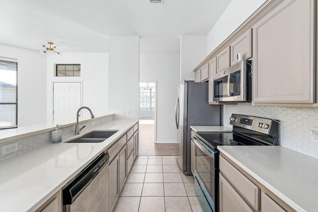 3833 Ives Way, Norman, OK 73072 - kitchen with appliances with stainless steel finishes, a sink, backsplash, light countertops, and a textured ceiling