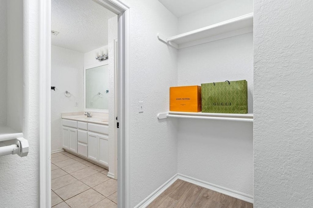 3833 Ives Way, Norman, OK 73072 - laundry area with a textured wall, light wood-type flooring, baseboards, and a sink