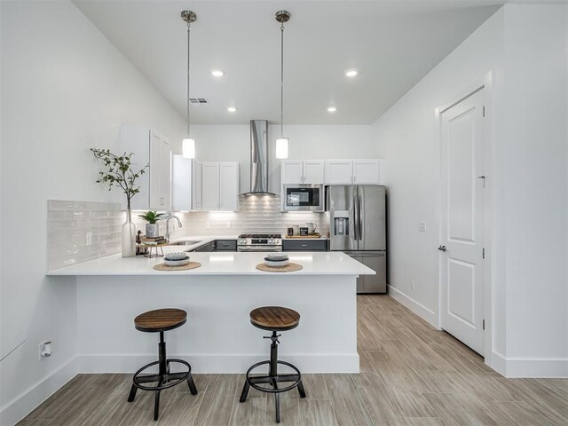 13112 Maplewood Ave, Oklahoma City, OK 73120 - kitchen featuring appliances with stainless steel finishes, wall chimney exhaust hood, light wood-style flooring, a breakfast bar, and recessed lighting