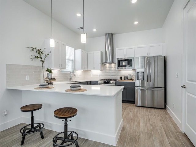 13112 Maplewood Ave, Oklahoma City, OK 73120 - kitchen featuring stainless steel appliances, wall chimney exhaust hood, a peninsula, a sink, and a kitchen bar