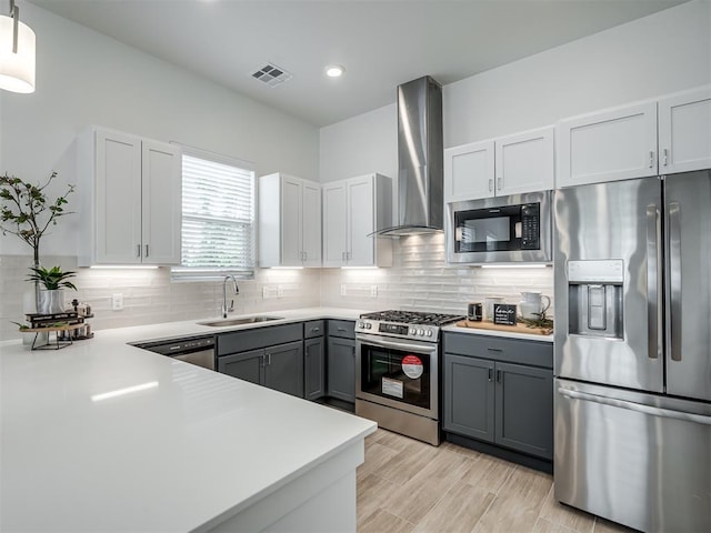 13112 Maplewood Ave, Oklahoma City, OK 73120 - kitchen featuring appliances with stainless steel finishes, a sink, wall chimney exhaust hood, gray cabinets, and tasteful backsplash