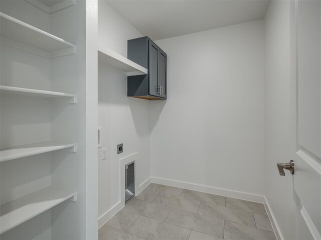 13112 Maplewood Ave, Oklahoma City, OK 73120 - laundry area with electric dryer hookup, cabinet space, baseboards, and light tile patterned flooring