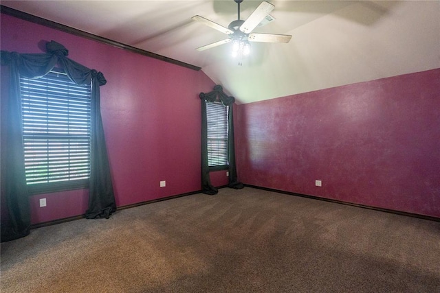 empty room with ornamental molding, vaulted ceiling, ceiling fan, carpet floors, and baseboards