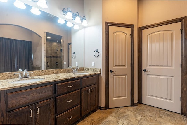 full bath with double vanity, a stall shower, and a sink