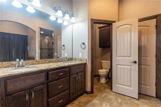 bathroom with double vanity, toilet, a stall shower, and a sink