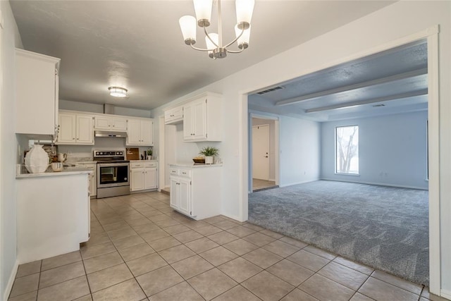 2408 Cypress Ct, Edmond, OK 73013 - kitchen with stainless steel range, light carpet, under cabinet range hood, light tile patterned floors, and a chandelier