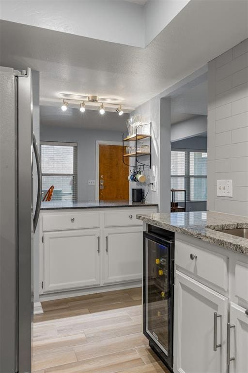 bar featuring light wood finished floors, wine cooler, and freestanding refrigerator