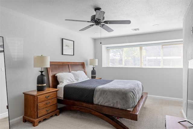 bedroom featuring visible vents, light colored carpet, baseboards, and a textured ceiling