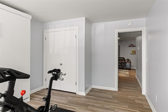 exercise room with light wood-style floors and baseboards