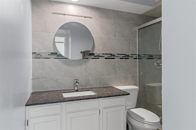 bathroom with a shower stall, toilet, vanity, and tile walls