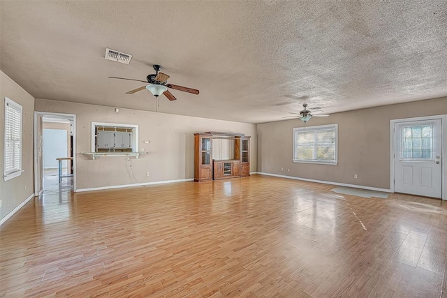 17421 E 1160th Rd, Sweetwater, OK 73666 - unfurnished living room with a ceiling fan, baseboards, visible vents, light wood-style flooring, and a textured ceiling