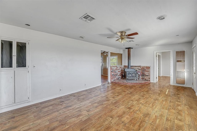 17421 E 1160th Rd, Sweetwater, OK 73666 - unfurnished living room with baseboards, visible vents, light wood finished floors, a wood stove, and ceiling fan