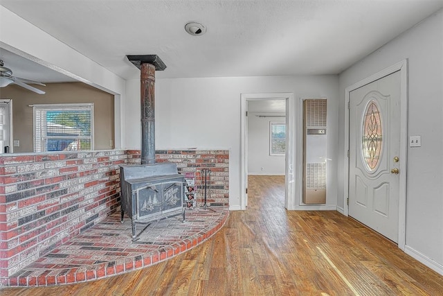 17421 E 1160th Rd, Sweetwater, OK 73666 - foyer entrance featuring a healthy amount of sunlight, a wood stove, a ceiling fan, and hardwood / wood-style floors