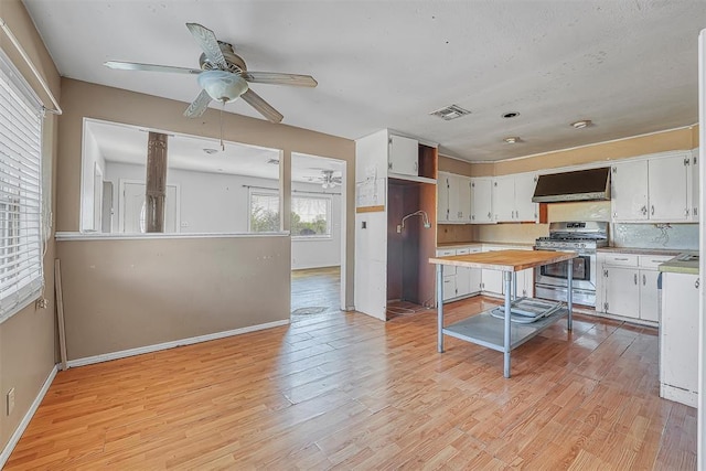 17421 E 1160th Rd, Sweetwater, OK 73666 - kitchen with wall chimney range hood, gas stove, visible vents, and light wood-style flooring