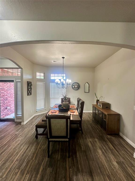 dining space featuring visible vents, a notable chandelier, wood finished floors, arched walkways, and baseboards