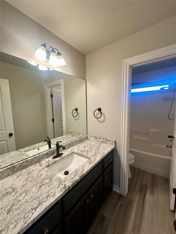 bathroom featuring shower / washtub combination, toilet, vanity, and wood finished floors
