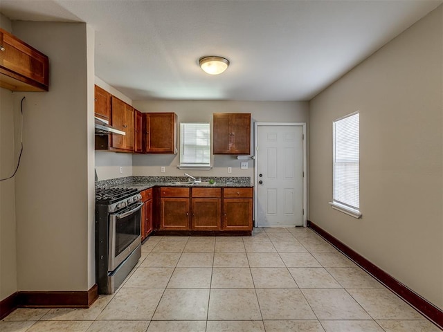 3604 NW 27th St, Oklahoma City, OK 73107 - kitchen with under cabinet range hood, a sink, dark countertops, light tile patterned flooring, and stainless steel range with gas stovetop