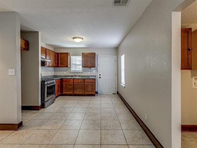 3604 NW 27th St, Oklahoma City, OK 73107 - kitchen featuring light tile patterned floors, visible vents, stainless steel range with gas stovetop, a sink, and wall chimney range hood