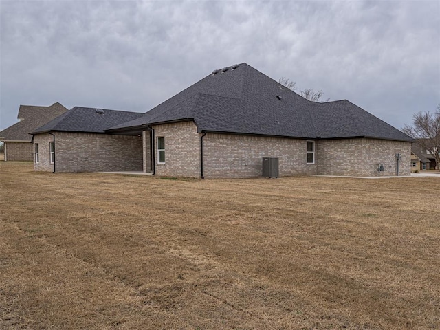 2292 NW 34th St, Newcastle, OK 73065 - view of side of home with roof with shingles, a yard, brick siding, and central AC unit