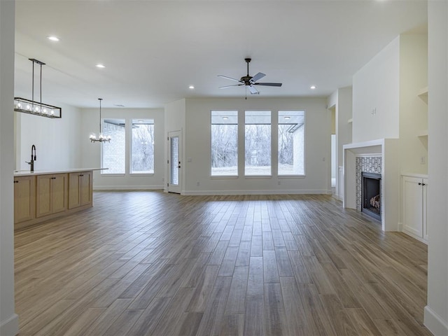 2292 NW 34th St, Newcastle, OK 73065 - unfurnished living room featuring a chandelier, ceiling fan, wood finished floors, a fireplace, and recessed lighting