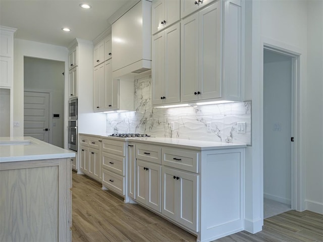 2292 NW 34th St, Newcastle, OK 73065 - kitchen with stainless steel appliances, premium range hood, tasteful backsplash, recessed lighting, and light wood finished floors
