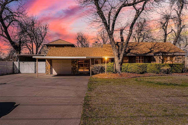 mid-century inspired home with fence, a front yard, driveway, stone siding, and an attached garage