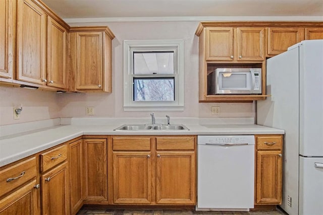 kitchen with brown cabinetry, white appliances, light countertops, and a sink
