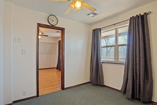 empty room with a ceiling fan, visible vents, and baseboards