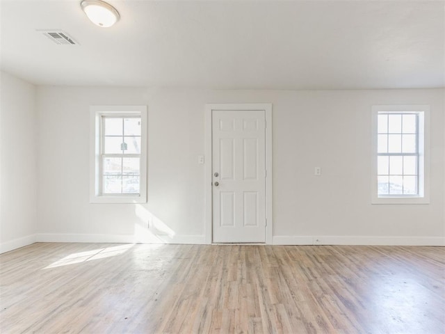 spare room featuring visible vents, baseboards, and wood finished floors