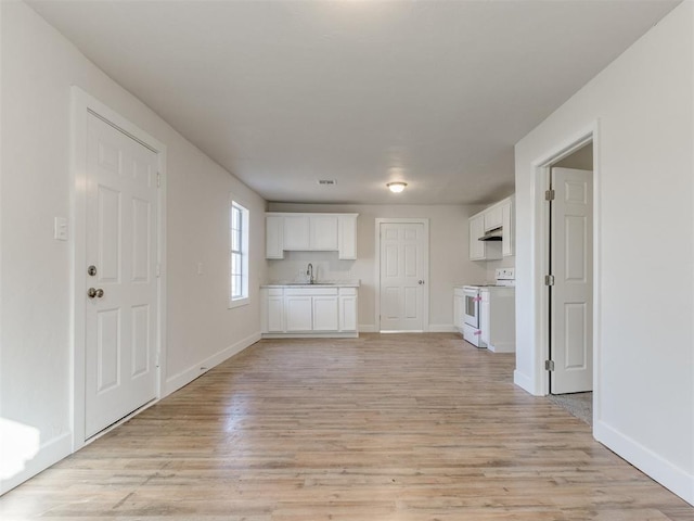 unfurnished living room with light wood-style flooring, baseboards, and a sink