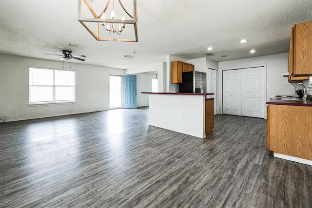 kitchen with a sink, dark countertops, open floor plan, and stainless steel fridge with ice dispenser