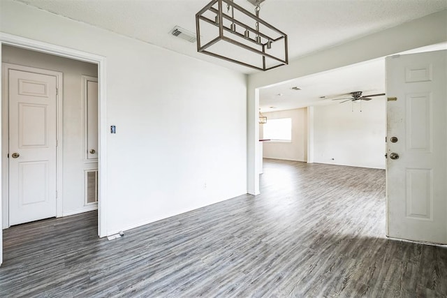 unfurnished room with ceiling fan with notable chandelier, wood finished floors, and visible vents