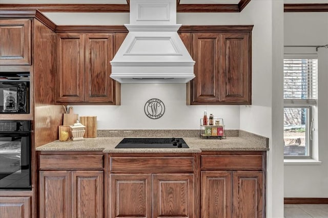 kitchen featuring black appliances, custom range hood, tile patterned flooring, crown molding, and light stone countertops