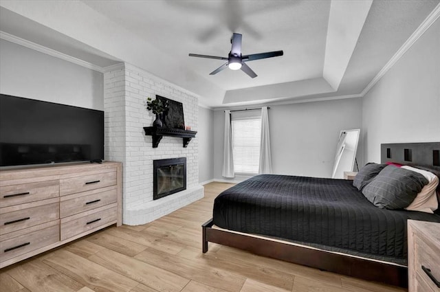2008 Powderhorn, Edmond, OK 73034 - bedroom featuring light wood-style flooring, a ceiling fan, ornamental molding, a tray ceiling, and a brick fireplace