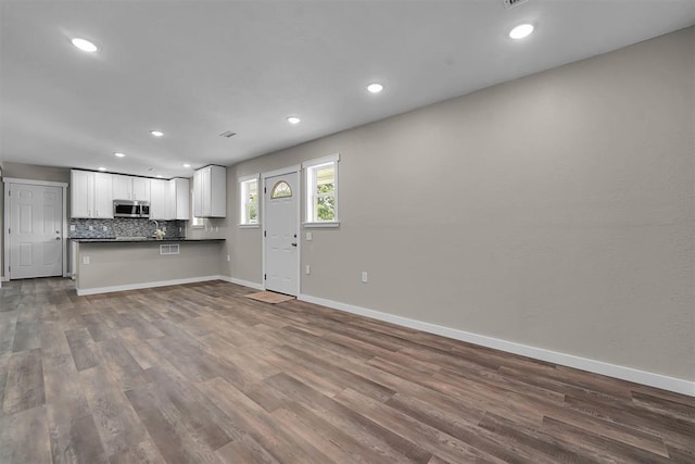 311 N 7th St, Sayre, OK 73662 - kitchen featuring stainless steel microwave, dark countertops, dark wood-style floors, open floor plan, and white cabinets