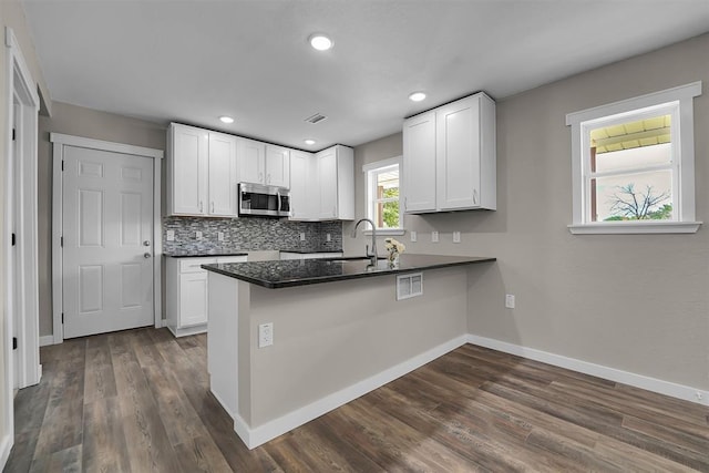 311 N 7th St, Sayre, OK 73662 - kitchen featuring stainless steel microwave, dark countertops, dark wood-style flooring, white cabinetry, and recessed lighting