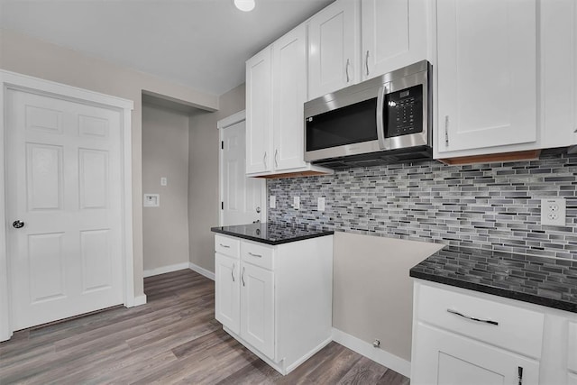 311 N 7th St, Sayre, OK 73662 - kitchen featuring stainless steel microwave, wood finished floors, backsplash, and white cabinets