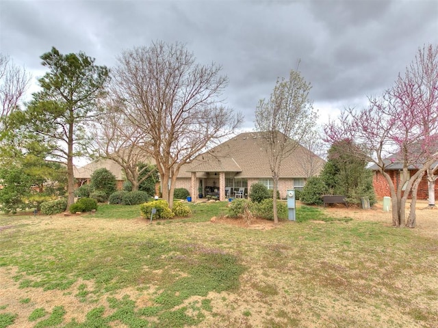 rear view of house with a lawn and brick siding