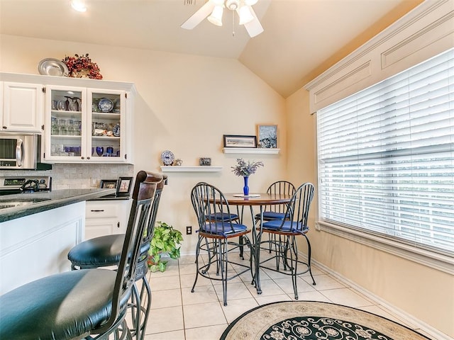 dining area with lofted ceiling, light tile patterned floors, a ceiling fan, and baseboards
