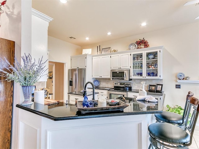 kitchen featuring visible vents, tasteful backsplash, stainless steel appliances, white cabinets, and glass insert cabinets