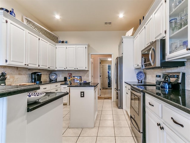 kitchen featuring visible vents, stainless steel appliances, white cabinets, light tile patterned floors, and glass insert cabinets