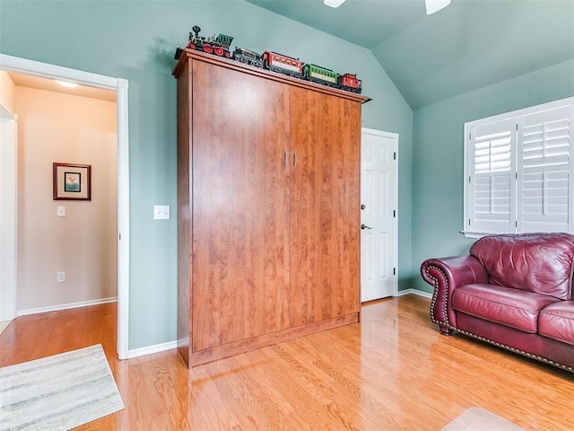 interior space featuring ceiling fan, baseboards, lofted ceiling, and light wood-style floors