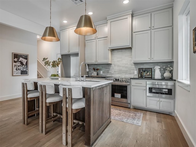 kitchen with a sink, light wood-style flooring, baseboards, and stainless steel range