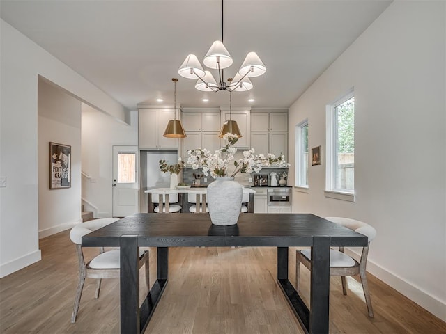 dining space featuring stairs, baseboards, wood finished floors, and a notable chandelier