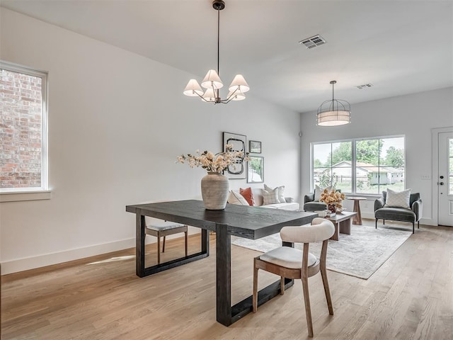 dining area featuring visible vents, light wood-style flooring, baseboards, and a notable chandelier