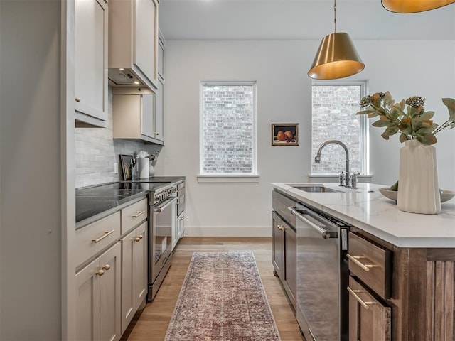 kitchen with light wood-style floors, appliances with stainless steel finishes, custom exhaust hood, and a sink