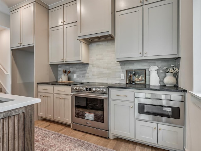 kitchen with light wood finished floors, decorative backsplash, and stainless steel appliances