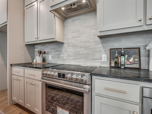 kitchen with custom exhaust hood, dark stone countertops, stainless steel range with electric cooktop, wood finished floors, and backsplash